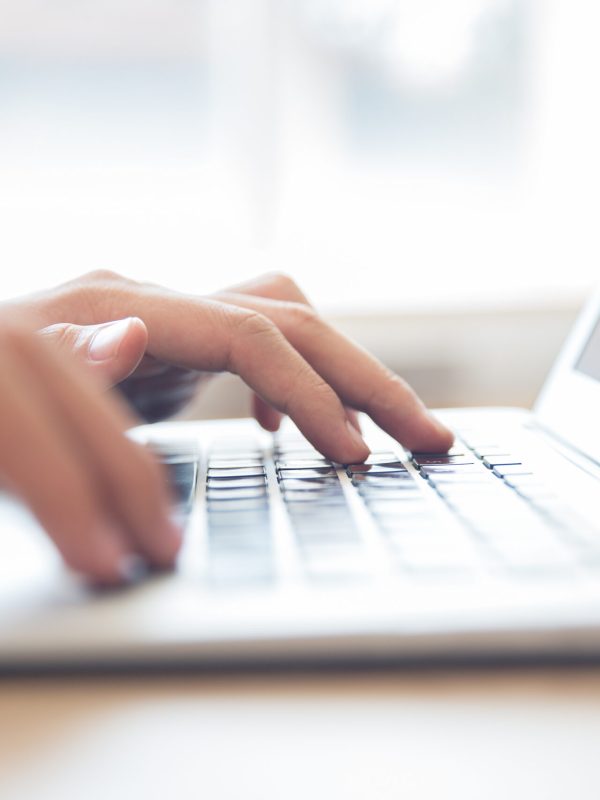 Close-up of male hands typing on laptop keyboard indoors. Businessman working in office or student browsing information